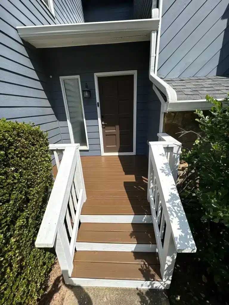 Blue siding entry with brown-stained steps and white rails — MG Barillas Painting
