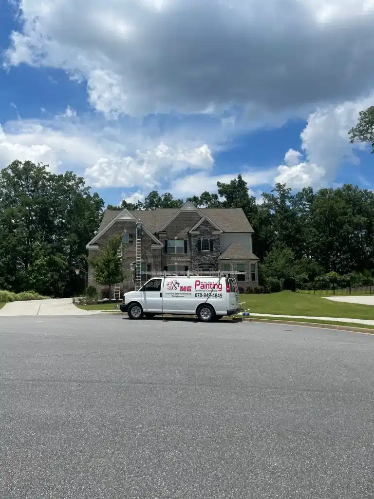 MG Barillas crew on ladders at a two-story brick home, company van out front — MG Barillas Painting