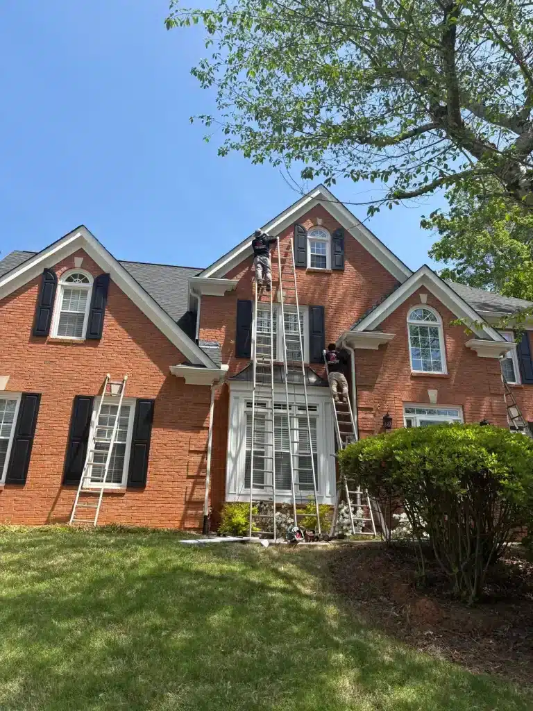 MG Barillas crew on ladders painting trim on a two-story brick home — MG Barillas Painting