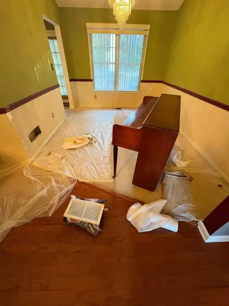 Dining room with green walls, floors covered before repainting — MG Barillas Painting