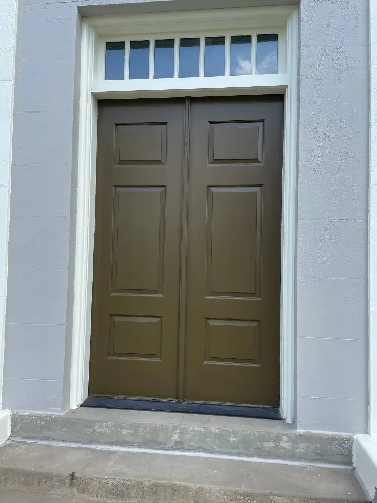 After: Double entry doors painted rich brown under a white transom