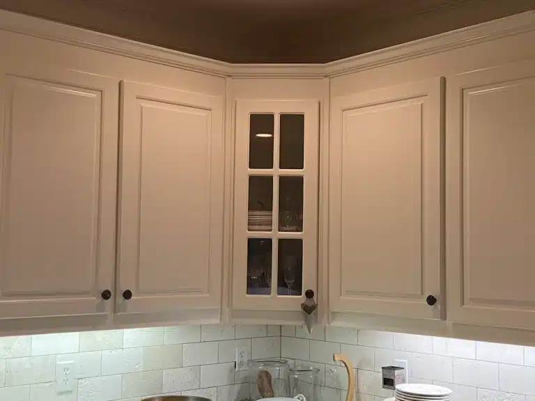Kitchen cabinets painted a soft cream with glass-front corner cabinet — MG Barillas Painting