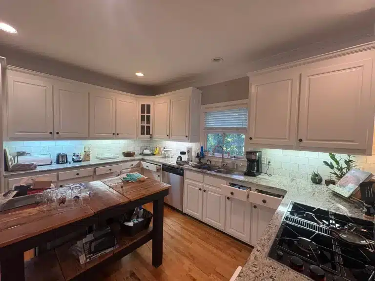 Kitchen cabinets painted bright white around a wood-top island — MG Barillas Painting