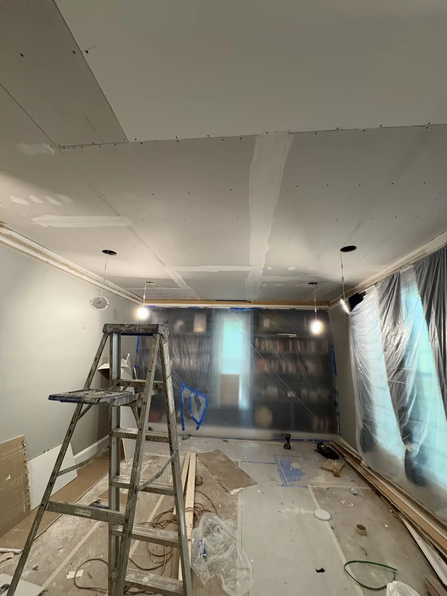 Painter on a ladder finishing basement walls and ceiling — MG Barillas Painting