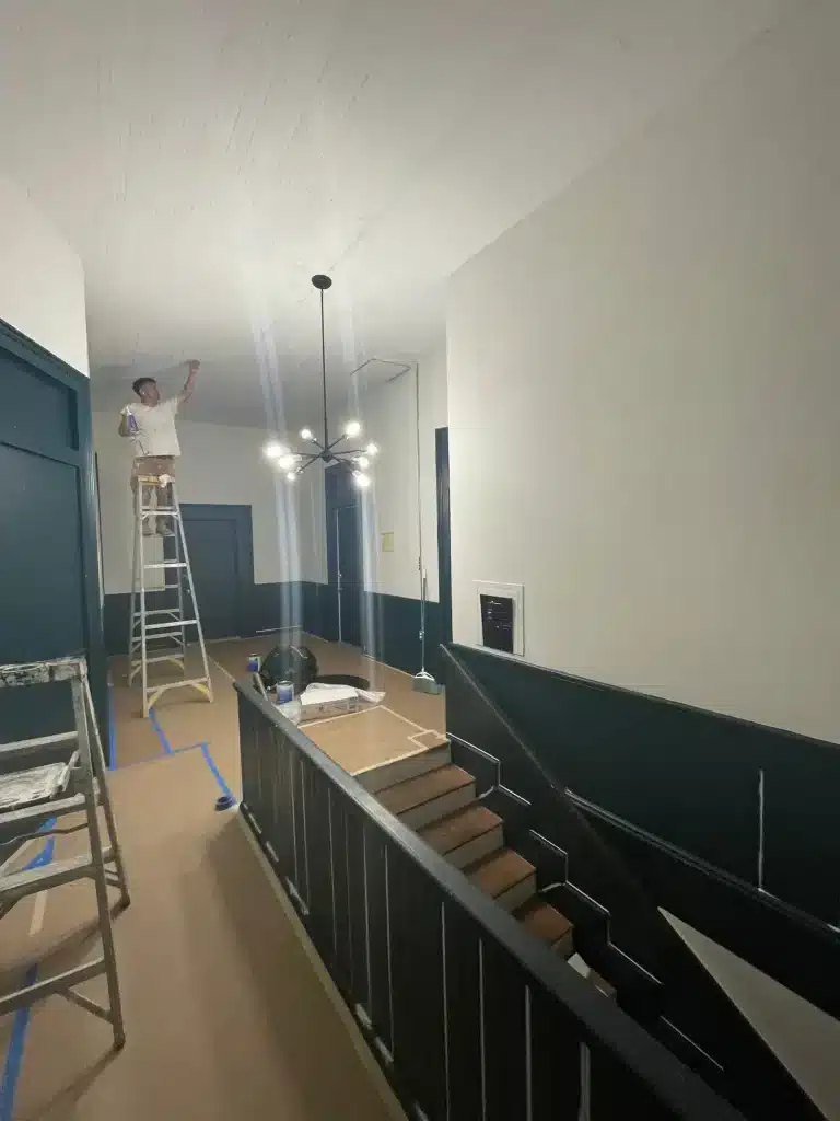 Painter on a ladder painting a beadboard hallway ceiling — MG Barillas Painting