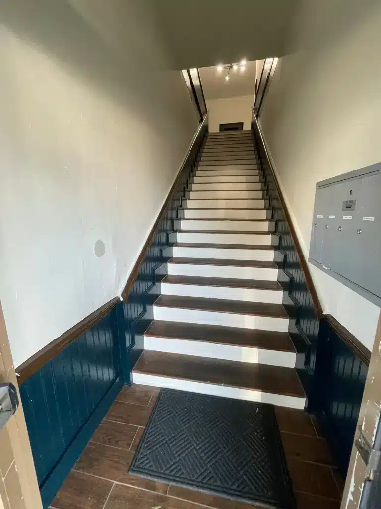 Stairwell with deep navy beadboard wainscoting and white stair risers — MG Barillas Painting