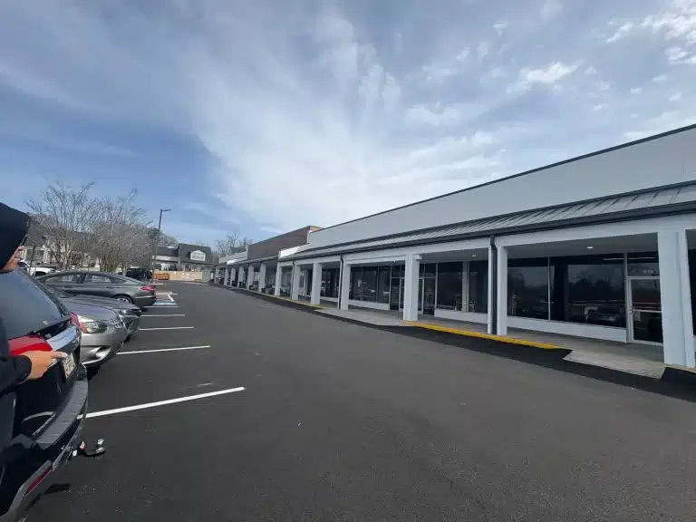 Strip center storefronts repainted crisp white with dark trim — MG Barillas Painting