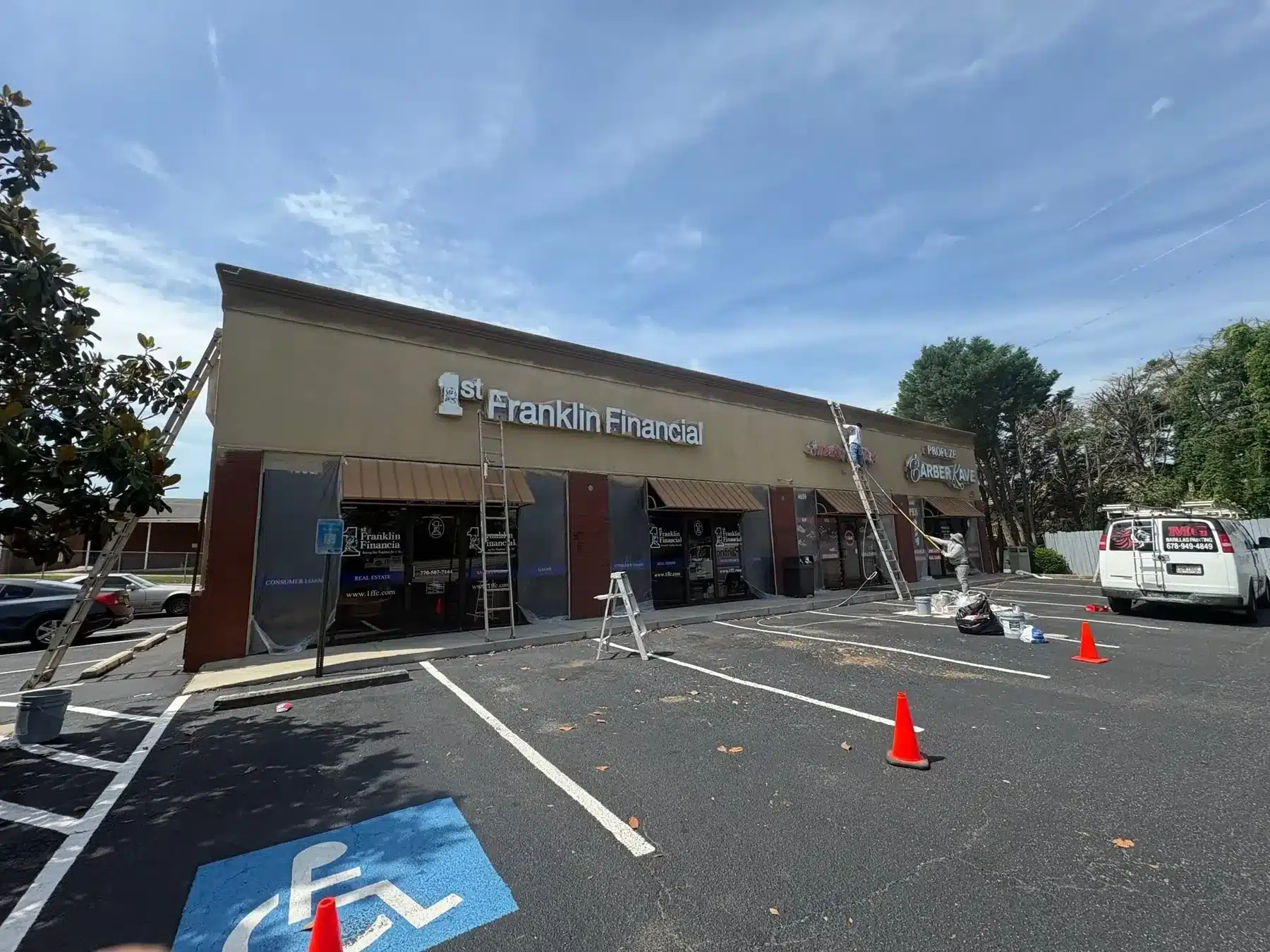 Before: Crew repainting a strip center exterior, with the MG Barillas van on site